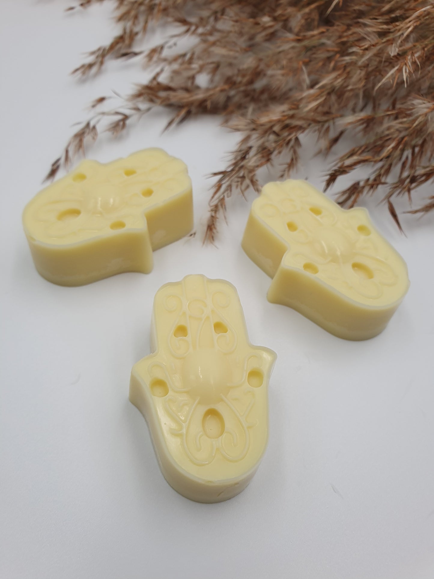 Mini Bodybutter / Körperbutter - Stücke in Form von Fatimas Hand auf weißem Hintergrund mit Schilfwedel