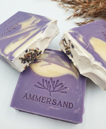 Drei Stücke handgemachte lilafarbene Naturseife auf weißem Hintergrund mit Schilfgras Nahaufnahme