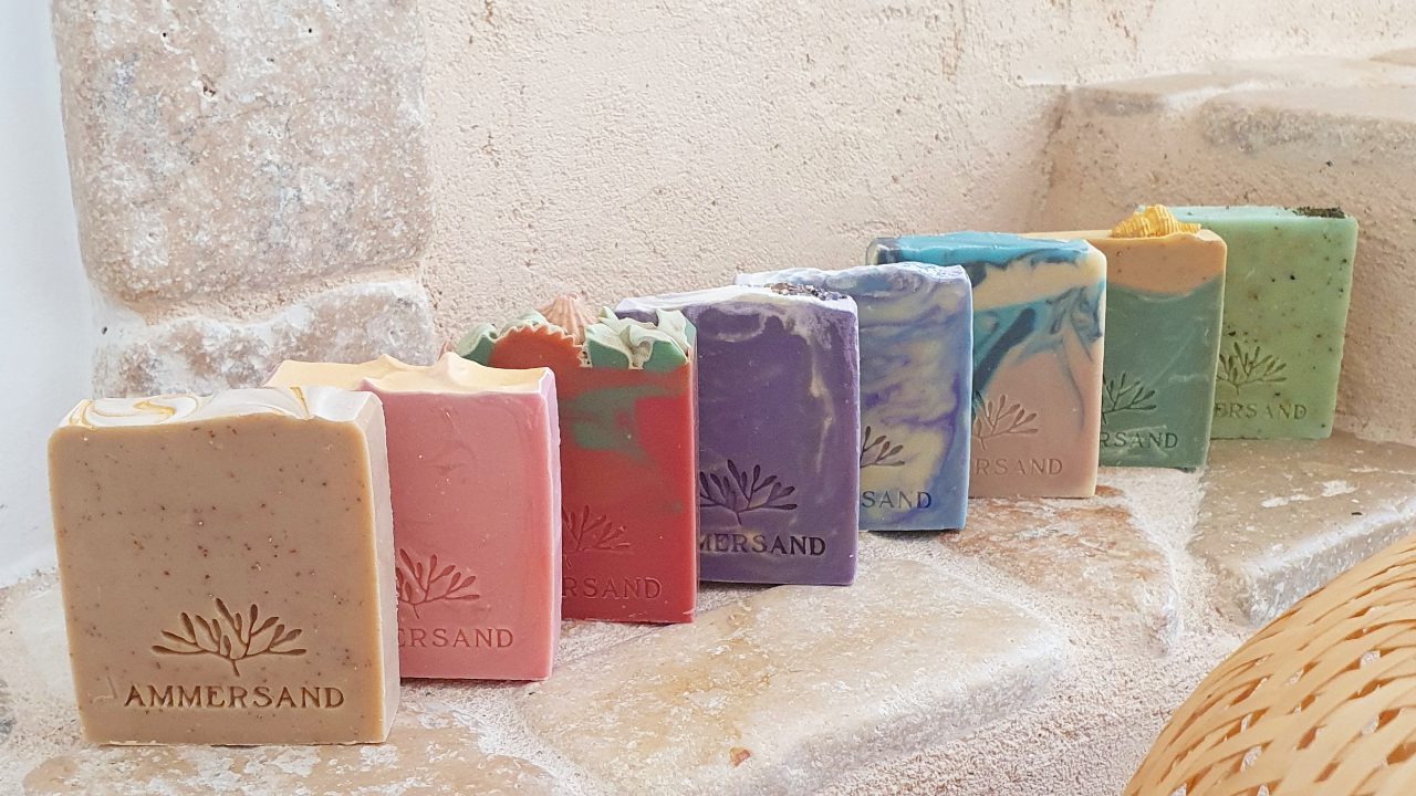 Bunte handgemachte Seifenstücke aneinandergereiht auf einer Natursteinmauer