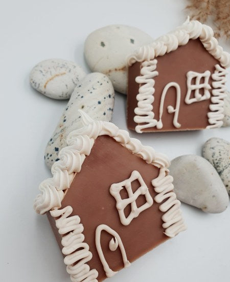 Handgemachte Seifenstücke in Form von Lebkuchen-Häusern auf weißem Hintergrund mit Schilfgras